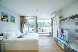 Una habitación de hotel moderna con cama, televisión y balcón con vistas.