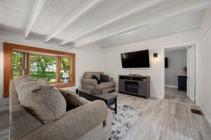 A modern living room with a sectional sofa, a flat-screen TV, and a fireplace. - The Brew Bungalow-Oneida Lakeside Getaway (Verona) (Canastota)