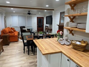 Ein gemütliches Wohnzimmer mit einer Couch, einem Esstisch und einer Küchenzeile mit Holzregalen.