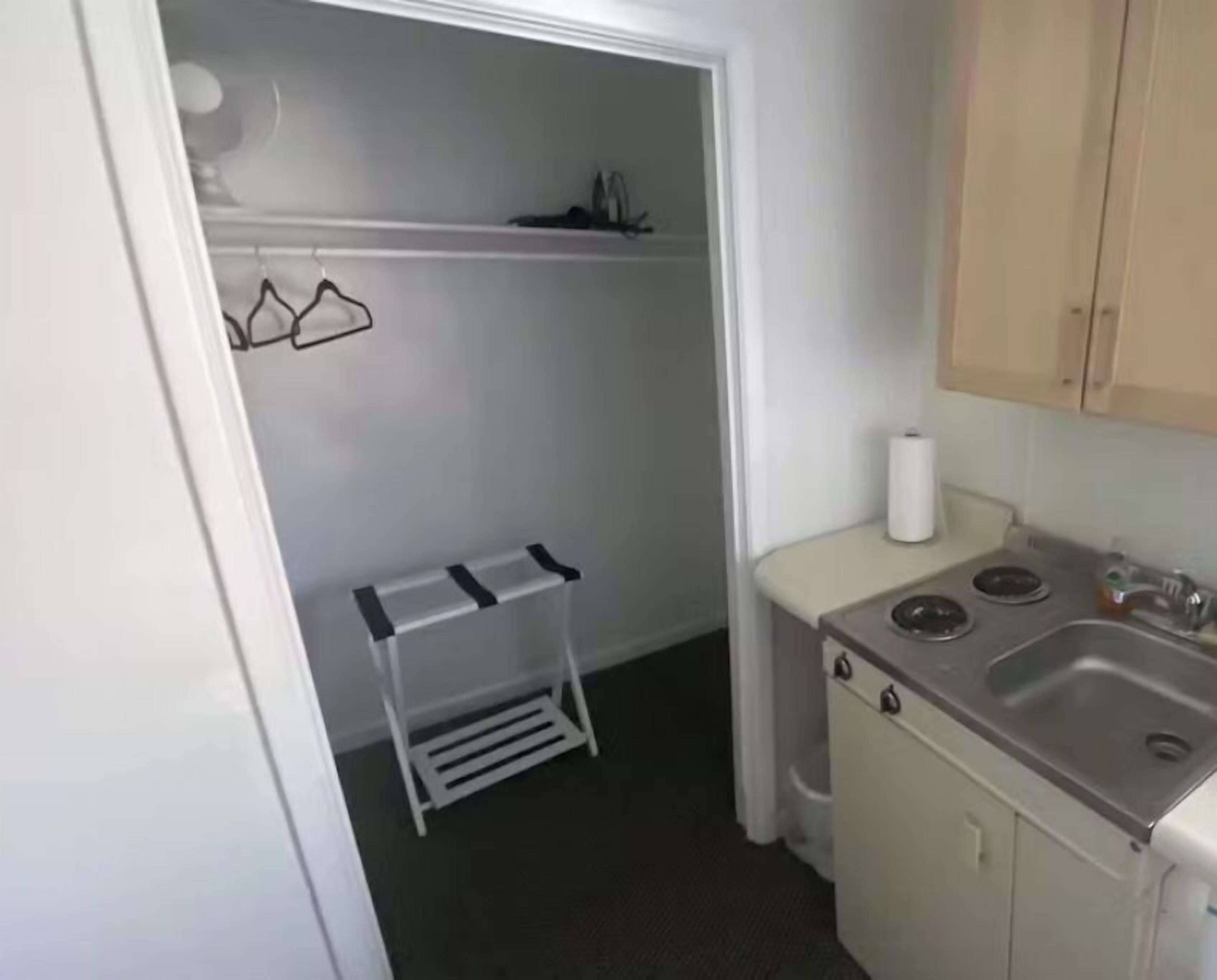 Une cuisine de taille réduite, équipée d’un évier, d’une cuisinière et d’un petit étendoir.