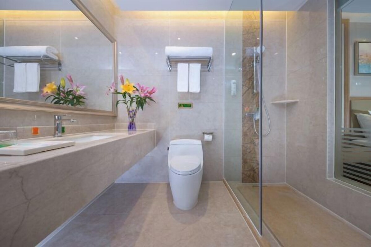 A modern bathroom with a glass shower enclosure, a white toilet, and a vanity with a mirror.