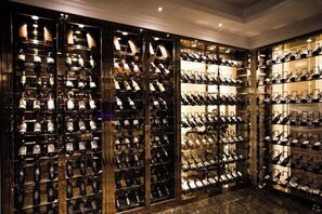 A wine cellar with multiple racks of wine bottles, illuminated by overhead lighting. - Vienna Hotel (Qingyuan Zhongshan Park Century Plaza) (Qingyuan)