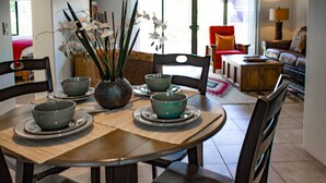 Zona pranzo con tavolo rotondo, quattro sedie e un vaso con fiori.
