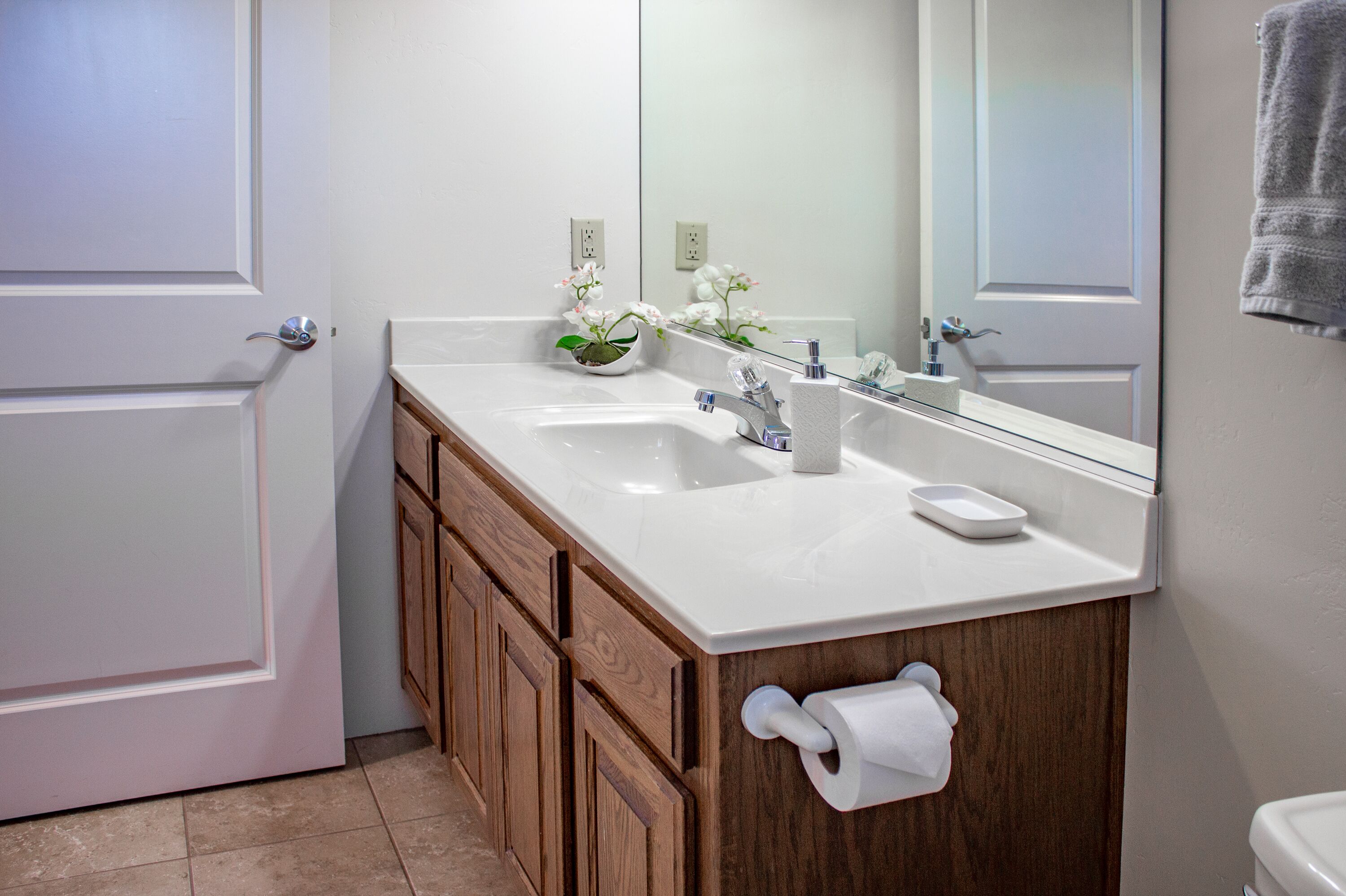 A bathroom with a white sink, wooden cabinets, a mirror, and a towel rack.