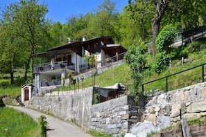 A hillside house with a stone retaining wall, a balcony, and a flag. - Casa Busso, Esino Lario, Italy (Esino Lario)