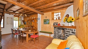 A rustic interior with a wooden dining area, a stone fireplace, and a sofa with colorful cushions. - Casa Busso, Esino Lario, Italy (Esino Lario)