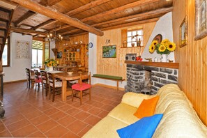 A rustic interior with a wooden dining area, a stone fireplace, and a sofa with colorful cushions. - Casa Busso, Esino Lario, Italy (Esino Lario)