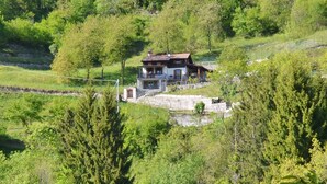 A two-story house with a balcony, surrounded by lush greenery and trees. - Casa Busso, Esino Lario, Italy (Esino Lario)