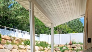 A covered patio area with concrete steps leading to a seating area. - Cozy Cabin Themed Basement (Morgan)