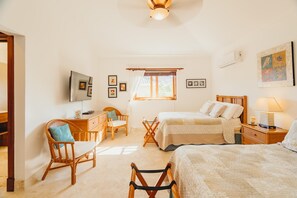 Un dormitorio con dos camas, un escritorio, una silla y un televisor.