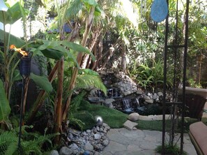 A garden with a small waterfall, rocks, and lush greenery. - Shared Home (Inglewood)
