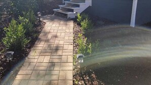 Una casa amb un camí empedrat que porta a la porta principal, envoltada de verdura i un petit jardí.
