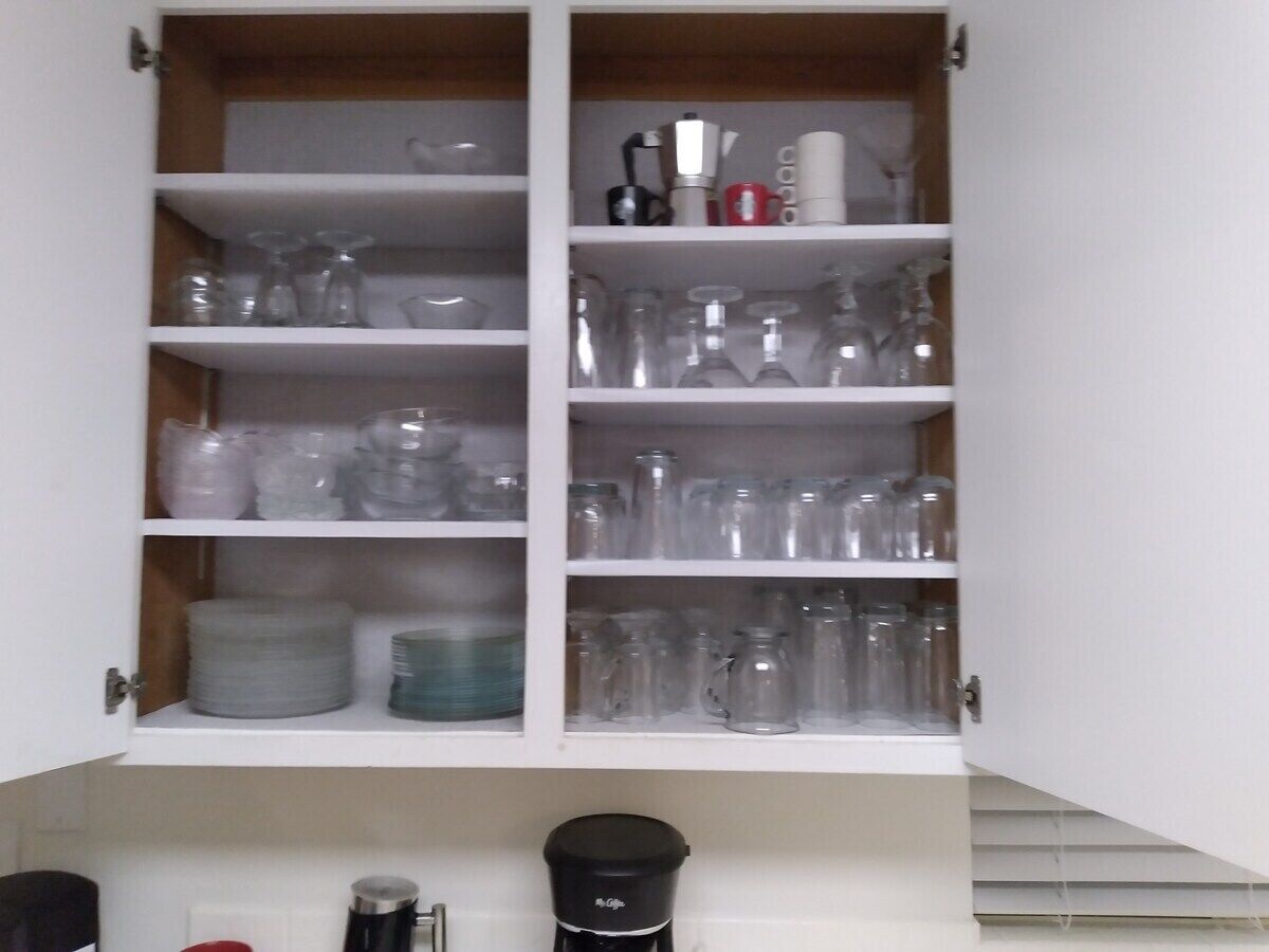 Un meuble de cuisine doté de plusieurs étagères où sont rangés divers récipients en verre, ainsi qu’une machine à café.