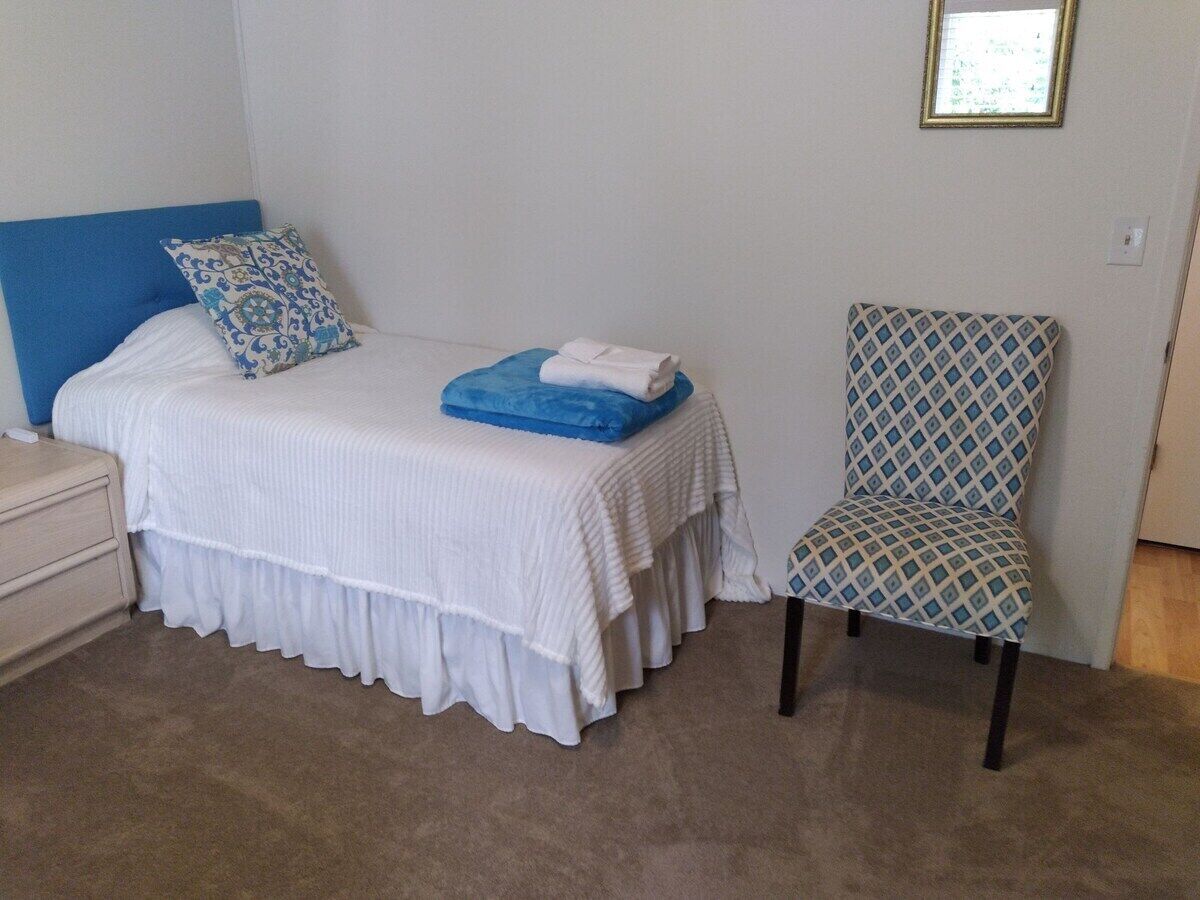 A bedroom with a bed, a chair, and a nightstand.