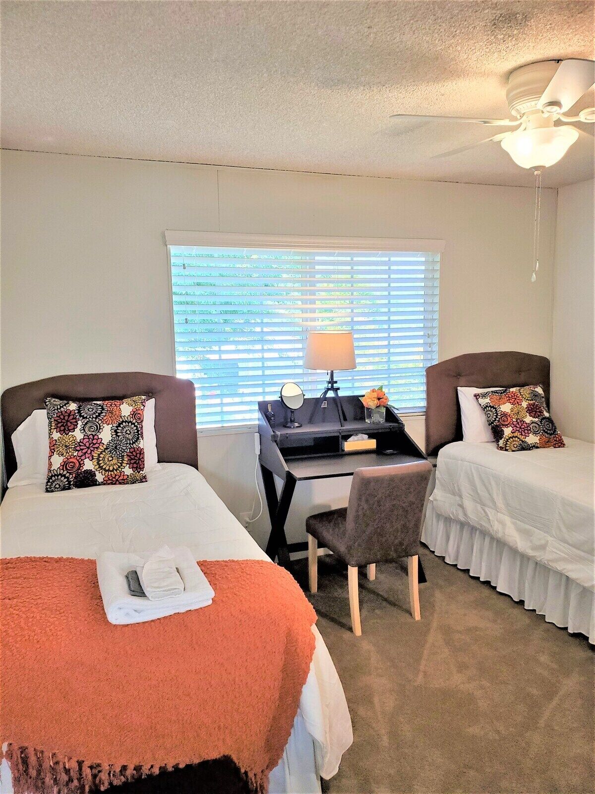 A hotel room with two beds, a desk, and a chair.