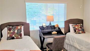 A hotel room with two beds, a desk, and a chair.