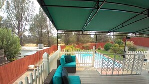 Eine überdachte Terrasse im Freien mit zwei Korbuscheln und einem Pool im Hintergrund.