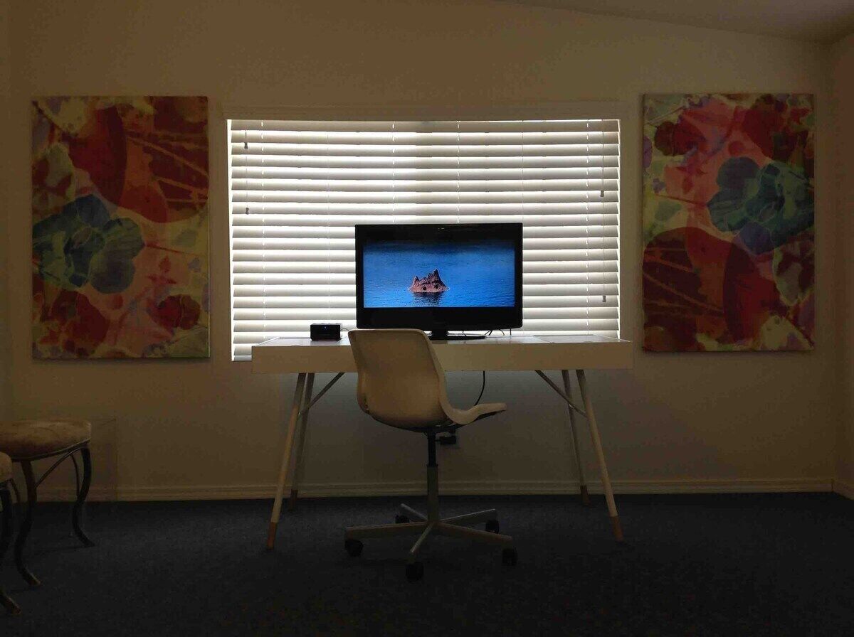 A room with a desk, a chair, and a television on a stand.