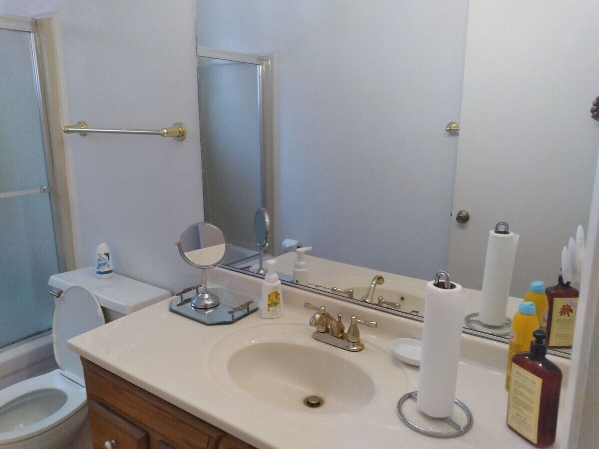 A bathroom with a sink, mirror, toilet, and shower.