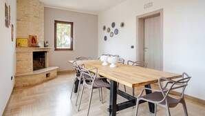 Un comedor con una mesa y sillas de madera, una chimenea de ladrillo y platos decorativos en la pared.