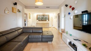 Una sala de estar moderna con un sofá modular, un televisor de pantalla plana y un mueble de entretenimiento de madera.
