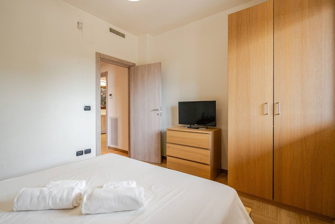 Habitación de hotel con una cama, un televisor en un aparador de madera y un armario.