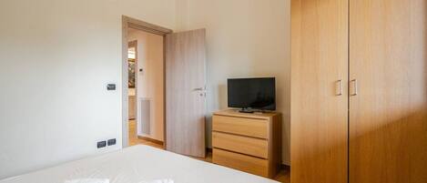 Habitación de hotel con una cama, un televisor en un aparador de madera y un armario.