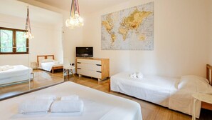 Una habitación de hotel moderna con una cama grande, una cama más pequeña, un escritorio, un televisor, un aparador de madera y un mapa del mundo en la pared.