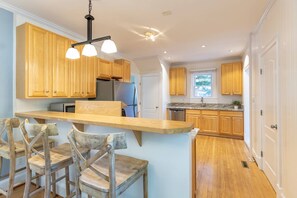 A kitchen with wooden cabinets, a built-in island, and a dining area with rustic chairs.