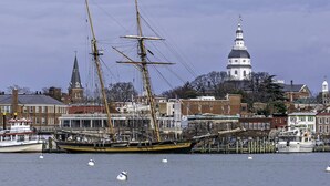 A historic ship docked at a harbor with a prominent church and a white dome building in the background. - USNA Home Steps to Stadium Dog-Friendly w Parking (Annapolis)