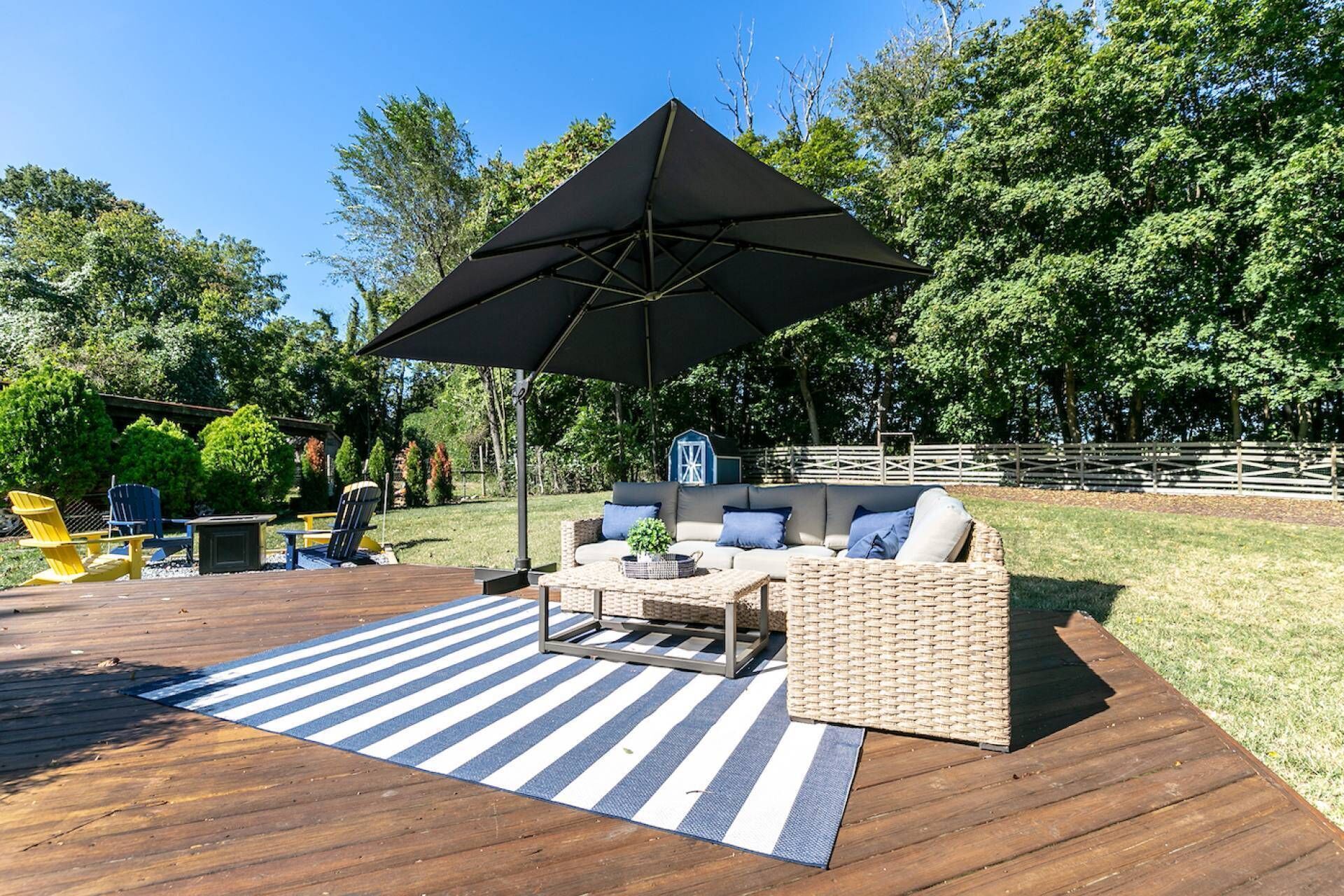 A deck with outdoor furniture, including a sofa and chairs, under a large umbrella.