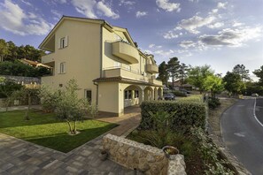 A two-story building with a balcony, a paved driveway, and a well-maintained lawn.