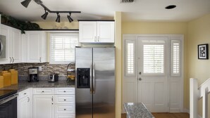 A kitchen with white cabinets, a stainless steel refrigerator, a coffee maker, and a toaster.
