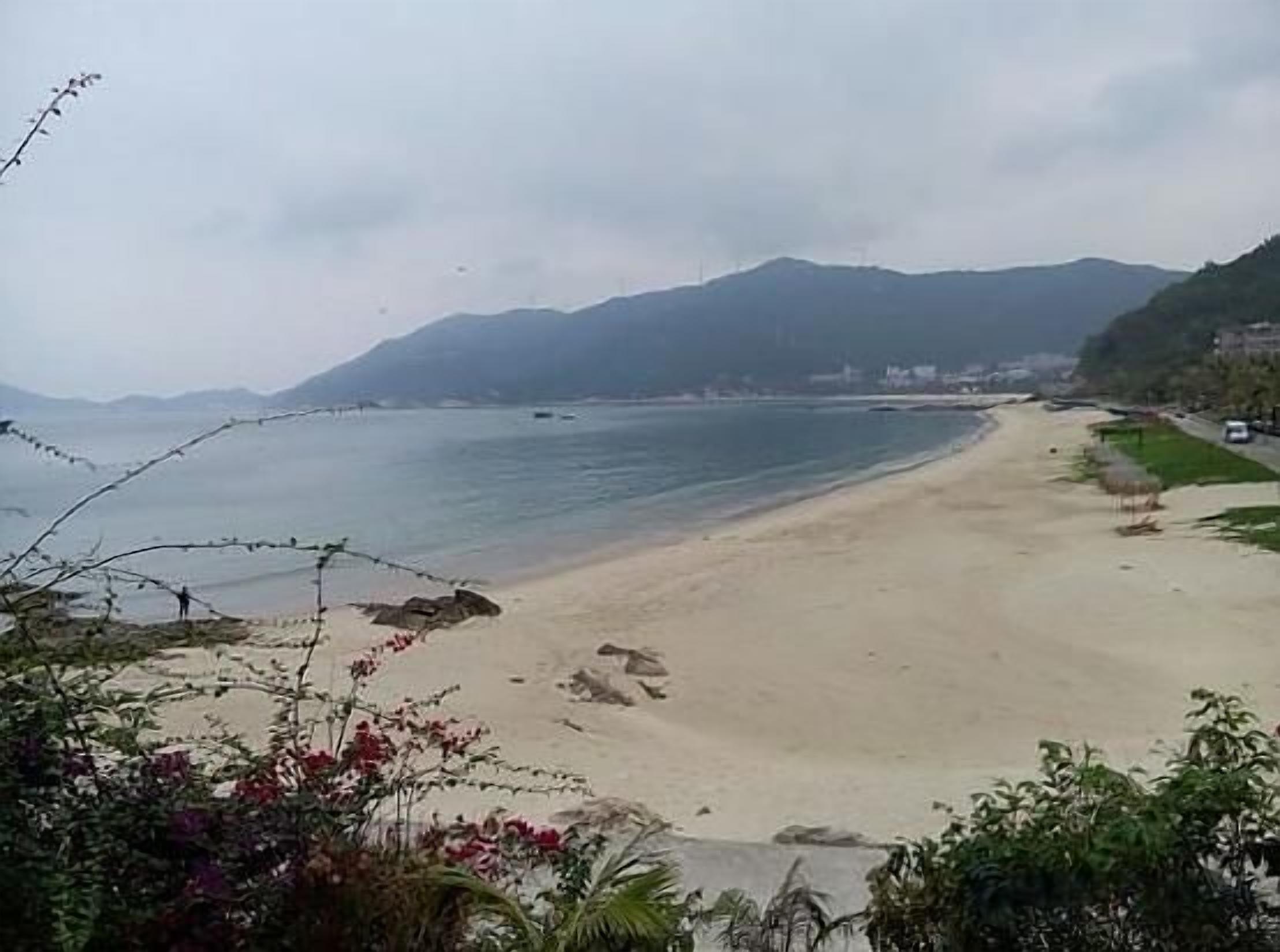 A beach with a clear view of the sea and distant mountains.