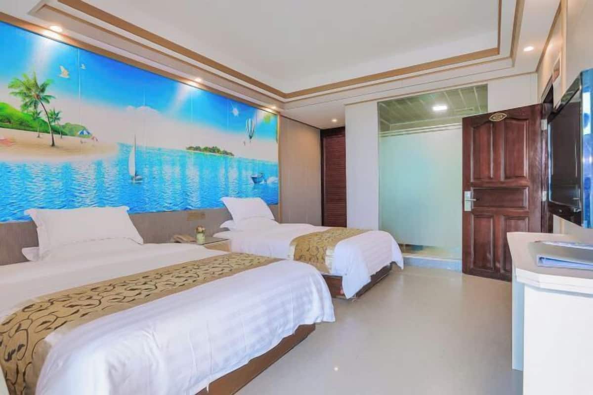 A hotel room with two beds, a mural of a beach scene, and a wooden door.