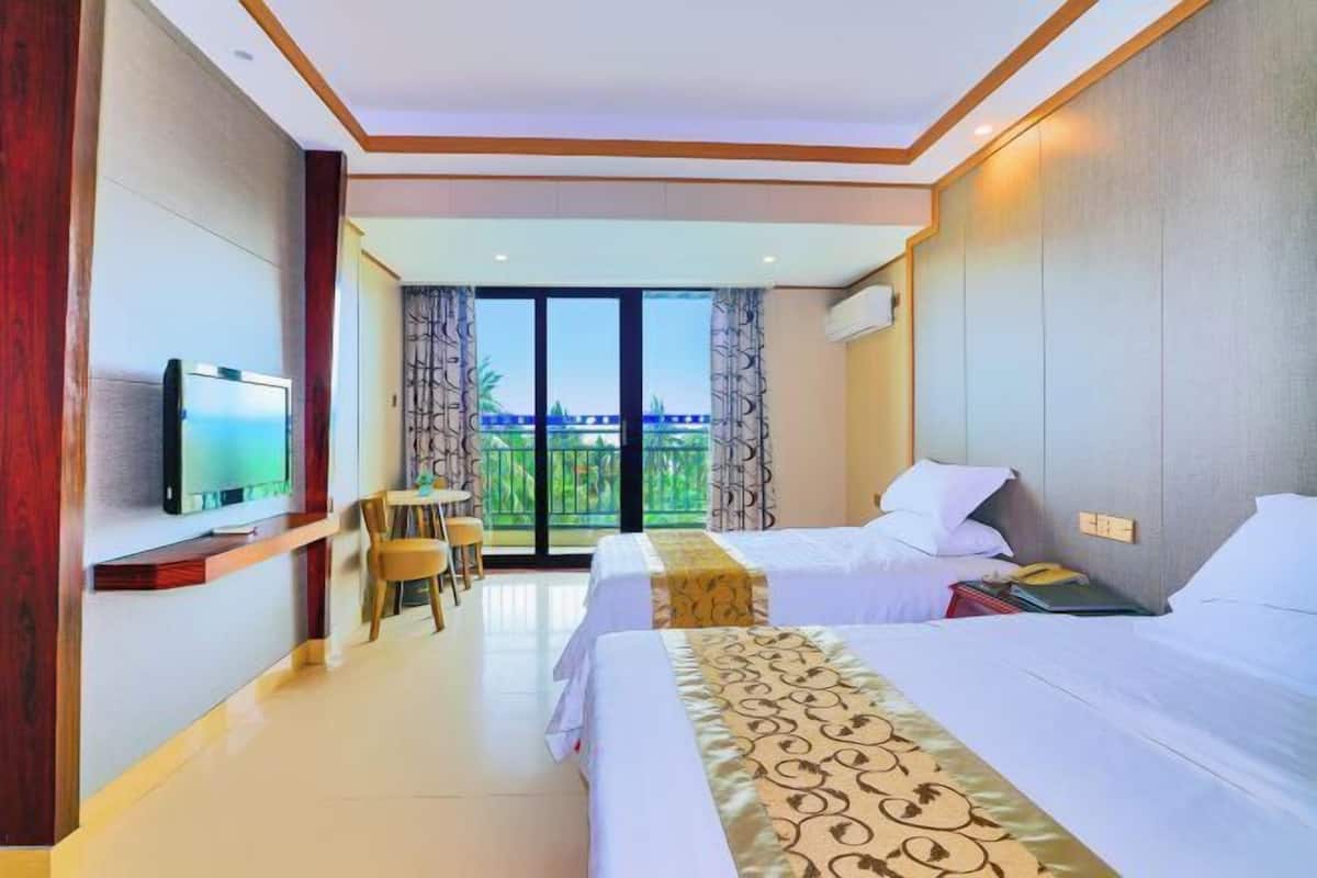 A hotel room with two beds, a TV, a balcony with a view, and a small desk area.