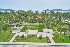 A resort with palm trees, a paved walkway, and a view of the sea. - Haidu Hotel (Taishan)