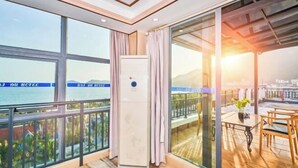 A balcony with a view of the sea, a table with chairs, and a large window with curtains. - Haidu Hotel (Taishan)