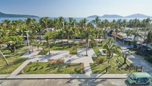 A coastal resort with palm trees, a parking area, and a view of the sea and mountains. - Haidu Hotel (Taishan)