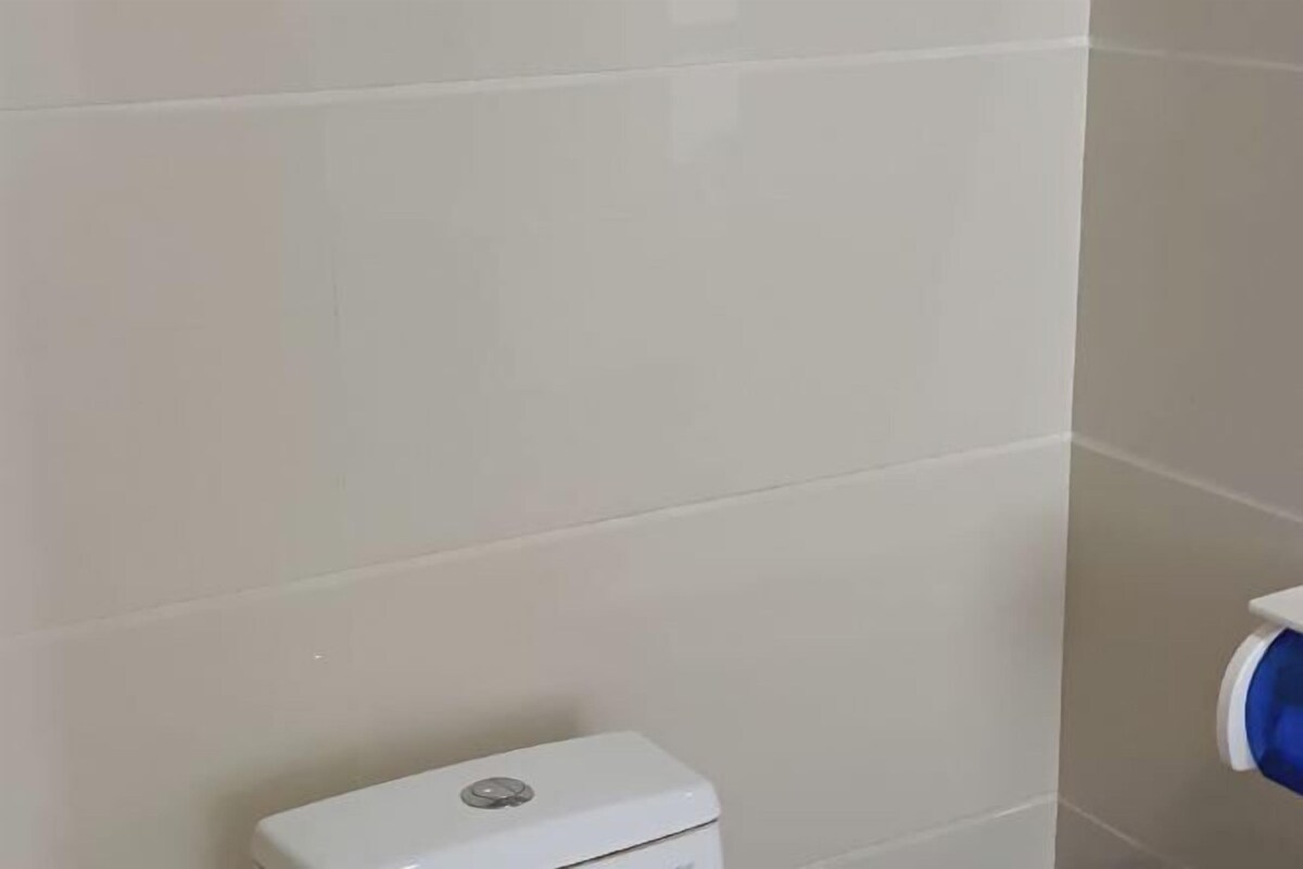 A bathroom with white tiles and a white toilet.