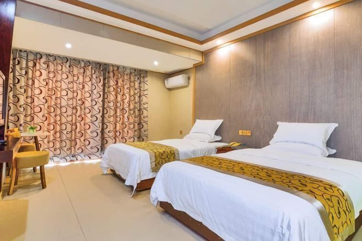 A hotel room with two beds, a desk, and a chair.