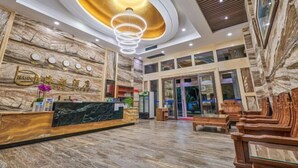 A hotel lobby with a marble reception desk, wooden benches, and a modern chandelier. - Haidu Hotel (Taishan)
