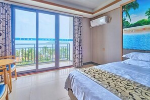 A hotel room with a bed, a table, and a view of a balcony with a railing. - Haidu Hotel (Taishan)