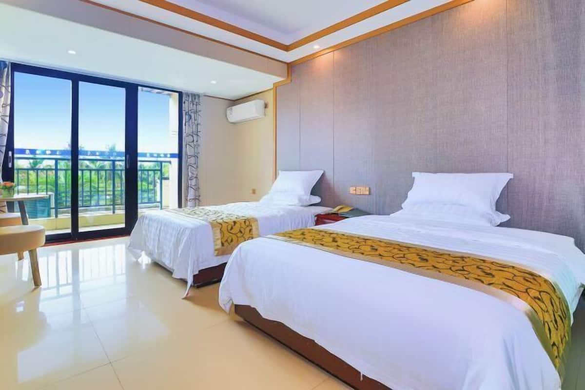 A hotel room with two beds, a balcony with a view, and a small seating area.