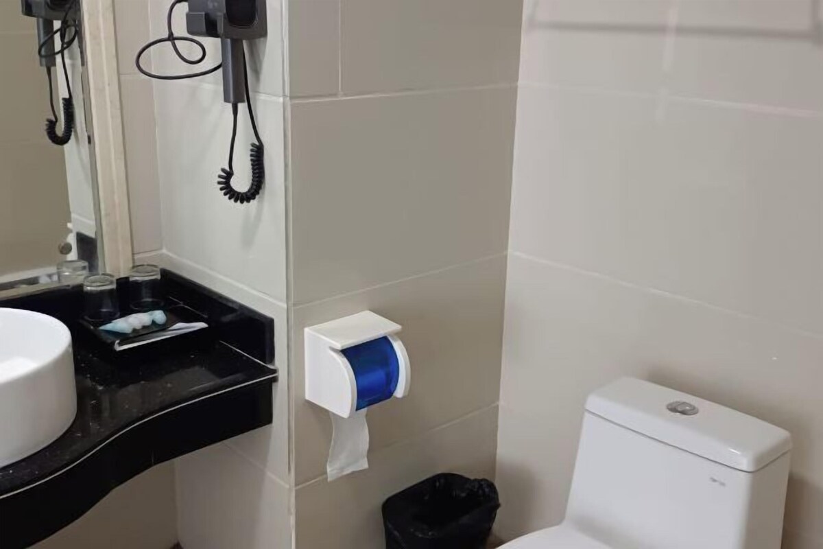 A bathroom with a white toilet, a black sink, a mirror, and a paper towel dispenser.