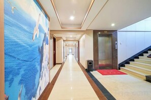 A hotel corridor with a long hallway, a red carpet, and an elevator. - Haidu Hotel (Taishan)
