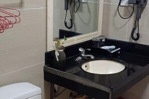 A bathroom with a black sink, a mirror, and two wall-mounted phones. - Haidu Hotel (Taishan)