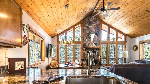 A spacious kitchen with granite countertops, a stone fireplace, and large windows.