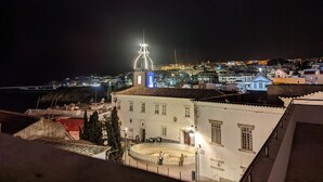 A coastal town at night with a prominent church featuring a lit tower. -  Beautiful charming flat, beautiful terrace facing the sea. Exceptional location (Albufeira)