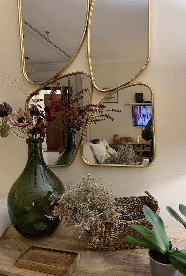 A room with a green vase, a woven basket, and a small potted plant on a wooden table.